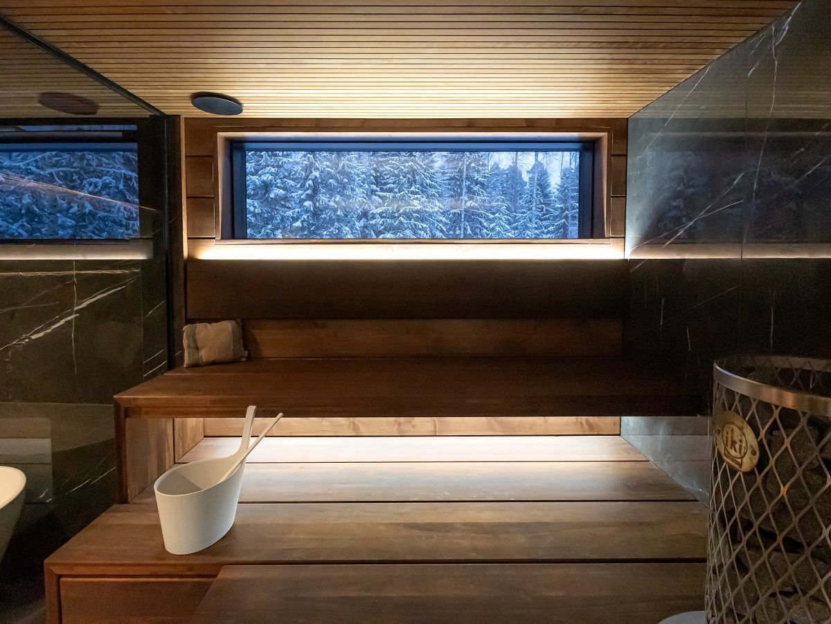 Illuminazione della sauna indirettamente da dietro lo schienale e sotto il soffitto, ripresa da davanti